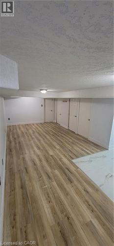 Spacious room featuring wood-finish plank flooring, white walls, and a textured ceiling - 716 Westminster Drive S Unit# Lower, Cambridge, ON - Indoor Photo Showing Other Room