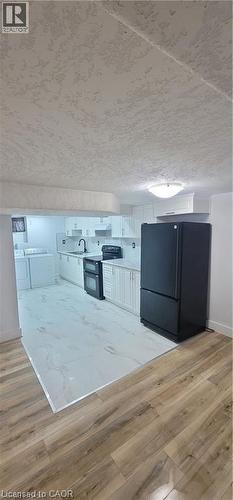 Kitchen area featuring white cabinetry, a black appliance suite, and a white tile floor - 716 Westminster Drive S Unit# Lower, Cambridge, ON - Indoor