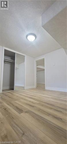 Room featuring wood-finish flooring, a flush-mount ceiling light, white walls, and a closet with mirrored sliding doors - 716 Westminster Drive S Unit# Lower, Cambridge, ON - Indoor Photo Showing Other Room