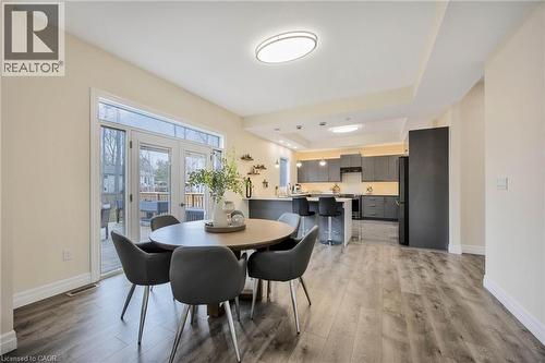 Open-concept kitchen and dining area featuring wood-finish flooring, a contemporary kitchen with dark cabinetry, a central island with bar seating, and French doors leading to an outdoor space - 6 Dorothys Drive, Oro-Medonte, ON - Indoor Photo Showing Dining Room