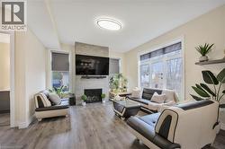 Open living area featuring wood-finish flooring and a contemporary fireplace with a stone-tile surround - 