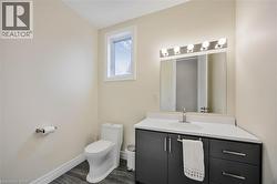 Bathroom featuring wood-finish flooring, a contemporary vanity with dark cabinetry, a white countertop, and a rectangular undermount sink with a brushed nickel faucet - 
