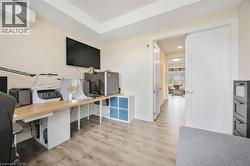 Versatile room featuring wood-finish flooring, a recessed ceiling detail, and a wall-mounted climate control unit - 