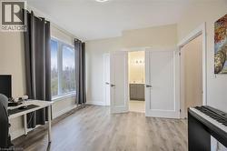 Spacious room featuring wood-finish flooring, a large window, and two paneled doors opening to an additional area - 