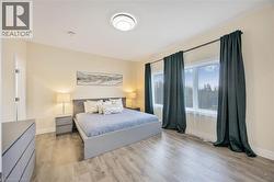 Spacious room featuring wood-finish flooring, a contemporary ceiling light fixture, and crown molding - 