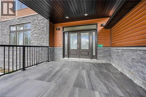 Inviting entry featuring a covered porch with large format tile flooring, a black metal railing, and a double entry door with sidelights - 6 Dorothys Drive, Oro-Medonte, ON - Outdoor With Exterior