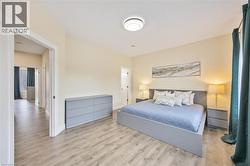 Spacious room featuring wood-finish flooring, a contemporary flush-mount ceiling light, and light-colored walls - 