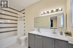 Bathroom featuring a dual-sink vanity with gray cabinetry, white countertops, and chrome fixtures - 
