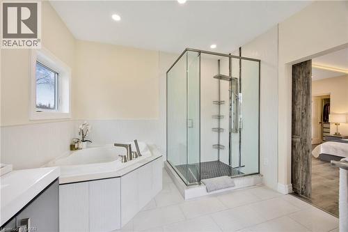 Corner soaking tub with deck-mounted brushed nickel fixtures, glass-enclosed shower with multiple sprayers, and a rustic barn door entry - 6 Dorothys Drive, Oro-Medonte, ON - Indoor Photo Showing Bathroom