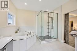 Corner soaking tub with deck-mounted brushed nickel fixtures, glass-enclosed shower with multiple sprayers, and a rustic barn door entry - 