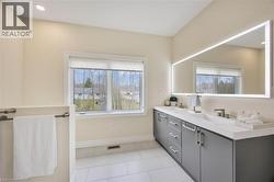 Modern bathroom featuring a double vanity with gray cabinetry and white countertops - 