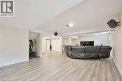 Spacious finished basement featuring light wood-finish flooring, recessed lighting, and white trim - 