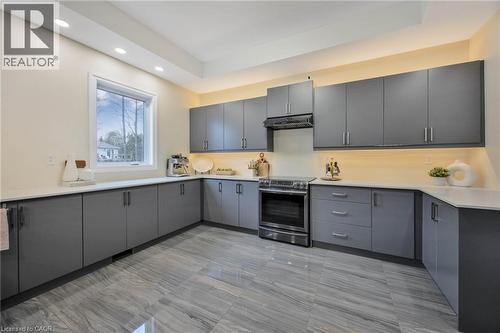 Contemporary kitchen featuring extensive gray cabinetry, light countertops, stainless steel range and hood, under-cabinet lighting, and large format tiled flooring - 6 Dorothys Drive, Oro-Medonte, ON - Indoor Photo Showing Kitchen