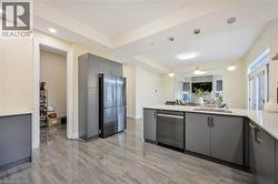 Open-concept kitchen featuring gray cabinetry, stainless steel appliances, a large island with sink, and light-toned countertops - 