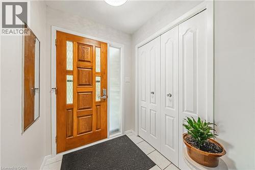 Front entry featuring a paneled wood-finish door with decorative glass inserts and a frosted sidelight - 235 Larch Street, Hamilton, ON - Indoor Photo Showing Other Room