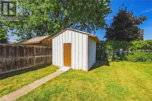 Detached storage shed with a brown door, set on a concrete pad with a concrete path - 235 Larch Street, Hamilton, ON - Outdoor