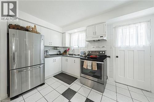 Kitchen featuring white cabinetry, stainless steel appliances, dark countertops, and a black and white checkered floor tile pattern - 235 Larch Street, Hamilton, ON - Indoor Photo Showing Kitchen