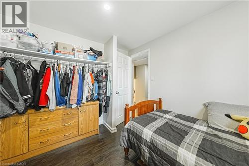 Integrated closet storage system with hanging rods, shelving, and wood-finish cabinetry featuring drawers - 235 Larch Street, Hamilton, ON - Indoor