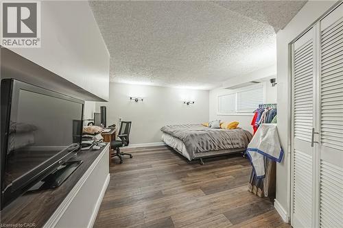 Spacious room featuring wood-finish flooring, white walls, and a textured ceiling - 235 Larch Street, Hamilton, ON - Indoor