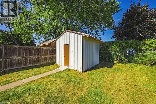 Backyard featuring a white metal storage shed with a brown door, a concrete pathway, and a wood fence - 235 Larch Street, Hamilton, ON - Outdoor