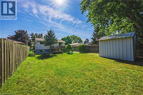 Expansive backyard featuring a lush lawn, mature trees, and a wooden privacy fence - 235 Larch Street, Hamilton, ON - Outdoor