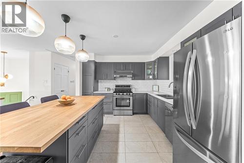 Kitchen featuring a large center island with a wood countertop, gray cabinetry, stainless steel appliances, and subway tile backsplash - 183 Harvard Road, Waterloo, ON - Indoor Photo Showing Kitchen With Double Sink With Upgraded Kitchen