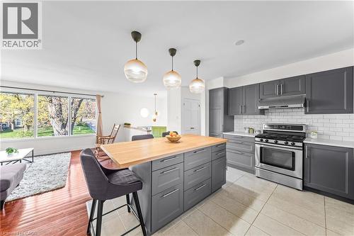 Contemporary kitchen featuring dark gray cabinetry, stainless steel appliances, a white subway tile backsplash, and a light wood-finish island countertop - 183 Harvard Road, Waterloo, ON - Indoor Photo Showing Kitchen