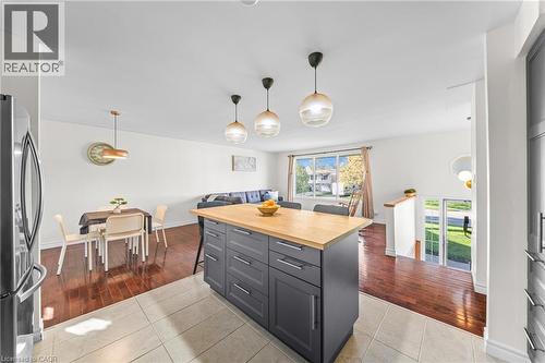 Spacious open-concept living area featuring an island with a wood-finish countertop, wood-finish flooring, and multiple pendant light fixtures - 183 Harvard Road, Waterloo, ON - Indoor