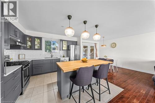 Modern kitchen featuring a central island with a wood-finish countertop, dark gray cabinetry, stainless steel appliances, white subway tile backsplash, and recessed lighting - 183 Harvard Road, Waterloo, ON - Indoor Photo Showing Kitchen With Upgraded Kitchen