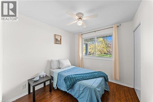 Room featuring a ceiling fan with light fixture, rich wood-finish flooring, and a large window with natural light - 183 Harvard Road, Waterloo, ON - Indoor Photo Showing Bedroom