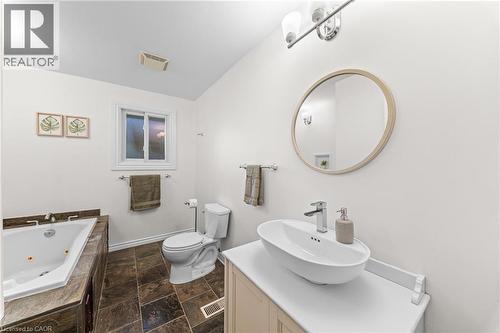 White oval vessel sink with chrome faucet, light wood-tone vanity, and round mirror - 183 Harvard Road, Waterloo, ON - Indoor Photo Showing Bathroom