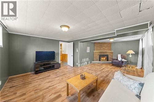 Living area featuring wood-finish flooring, a brick fireplace with a hearth, paneling, and an overhead light fixture - 183 Harvard Road, Waterloo, ON - Indoor Photo Showing Other Room With Fireplace