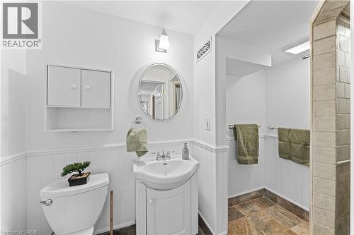 Bathroom featuring wainscoting, a pedestal sink, a wall-mounted medicine cabinet, a round mirror, and tiled flooring - 183 Harvard Road, Waterloo, ON - Indoor Photo Showing Bathroom
