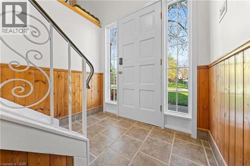 Entryway featuring a paneled front door with sidelight windows, wood-finish wainscoting, decorative wrought iron stair railing, and large format tile flooring - 183 Harvard Road, Waterloo, ON - Indoor Photo Showing Other Room