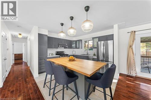 Contemporary kitchen featuring a center island with a wood-finish countertop, dark gray cabinetry, stainless steel appliances, and a white subway tile backsplash - 183 Harvard Road, Waterloo, ON - Indoor