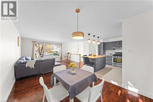 Open-concept living space featuring wood-finish flooring, a contemporary kitchen with gray cabinetry and stainless steel appliances, a kitchen island with a wood countertop, and modern pendant lightin - 183 Harvard Road, Waterloo, ON - Indoor Photo Showing Other Room