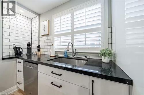 Kitchen featuring white shaker-style cabinetry with black hardware, black speckled countertops, stainless steel sink with gooseneck faucet, subway tile backsplash, and a built-in stainless steel dishw - 88 South Bend Road E Unit# Unit A, Hamilton, ON - Indoor Photo Showing Kitchen