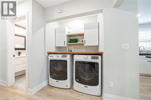 Dedicated laundry area featuring a wood-finish countertop, two white upper cabinets, and open wood shelving - 88 South Bend Road E Unit# Unit A, Hamilton, ON - Indoor Photo Showing Laundry Room