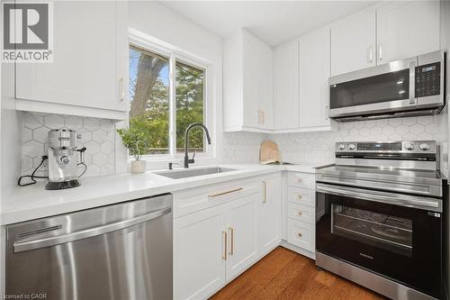 Modern kitchen featuring white shaker cabinetry with gold-tone hardware, white countertops, and a hexagonal tile backsplash - 1376 Royal Drive, Burlington, ON - Indoor Photo Showing Kitchen With Upgraded Kitchen