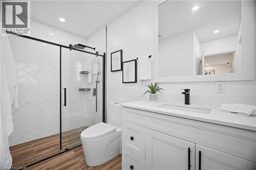 Modern bathroom featuring a glass-enclosed shower with black framing, white subway tile in a herringbone pattern, and wood-finish flooring - 1376 Royal Drive, Burlington, ON - Indoor Photo Showing Bathroom