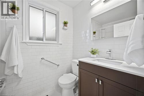 Contemporary bathroom featuring white subway tile walls, a frosted privacy window, a dark wood-finish vanity with a white countertop, and a chrome faucet - 1376 Royal Drive, Burlington, ON - Indoor Photo Showing Bathroom