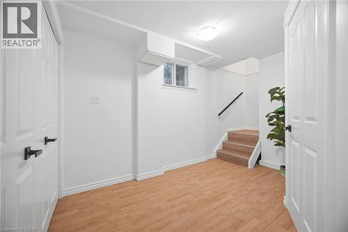 Finished lower level featuring wood-finish flooring, recessed window, and a prominent staircase with a black handrail - 1376 Royal Drive, Burlington, ON - Indoor Photo Showing Other Room
