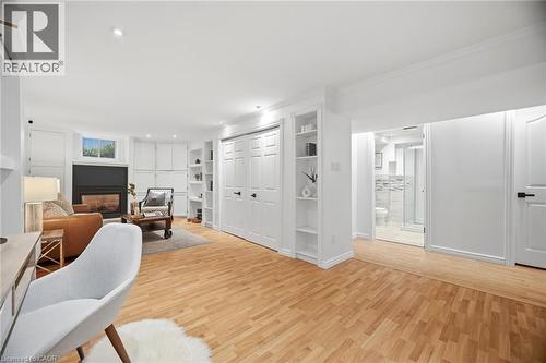 Lower-level living area with wood-finish flooring, a built-in fireplace, recessed lighting, and integrated shelving - 1376 Royal Drive, Burlington, ON - Indoor With Fireplace