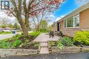 Front exterior featuring brick and stacked stone siding, a paver patio, established landscaping with mature trees, a multi-pane picture window, and a dark entry door - 1376 Royal Drive, Burlington, ON  - Outdoor 