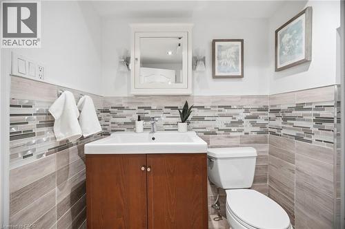 Bathroom featuring a wood-finish vanity with a white rectangular sink, mosaic tile backsplash, and a wall-mounted mirrored medicine cabinet - 1376 Royal Drive, Burlington, ON - Indoor Photo Showing Bathroom