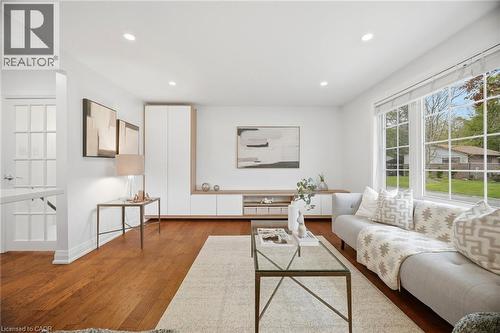 Living space featuring expansive windows, recessed lighting, wood-finish flooring, built-in cabinetry with natural wood accents, and a French pane door - 1376 Royal Drive, Burlington, ON - Indoor Photo Showing Living Room