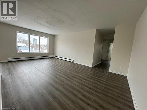 Spacious room featuring wood-finish flooring, white baseboards, and neutral wall paint - 232 Louisa Street Unit# 9A, Kitchener, ON - Indoor Photo Showing Other Room