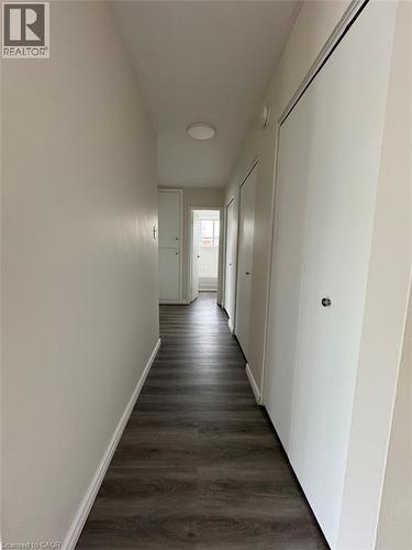 Hallway featuring wood-finish flooring, light neutral paint, a flush-mount ceiling light, and white bi-fold closet doors - 232 Louisa Street Unit# 9A, Kitchener, ON - Indoor Photo Showing Other Room