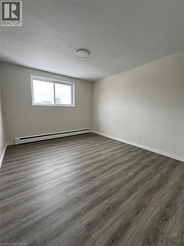 Spacious room featuring wood-finish flooring, neutral-toned walls, and a large window - 232 Louisa Street Unit# 9A, Kitchener, ON - Indoor Photo Showing Other Room