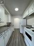 Galley kitchen featuring white cabinetry, dark gray countertops, stainless steel sink, and wood-finish flooring - 232 Louisa Street Unit# 9A, Kitchener, ON  - Indoor Photo Showing Kitchen 